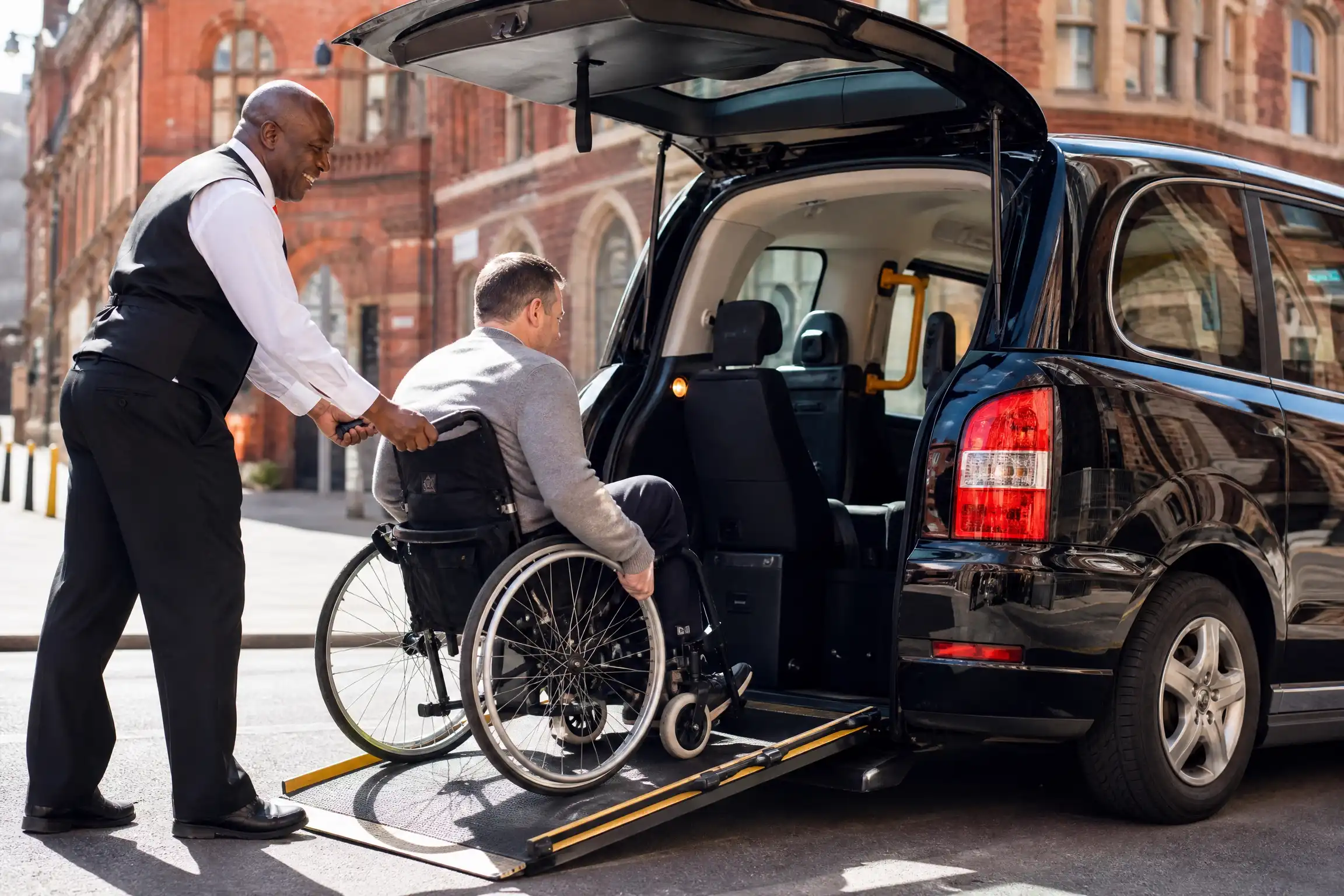 Driver assisting wheelchair passenger at pickup